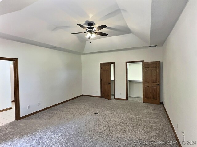 unfurnished bedroom with ceiling fan, light carpet, and a tray ceiling