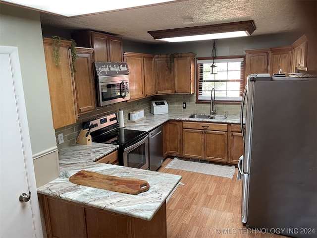 kitchen featuring stainless steel appliances, sink, backsplash, and kitchen peninsula