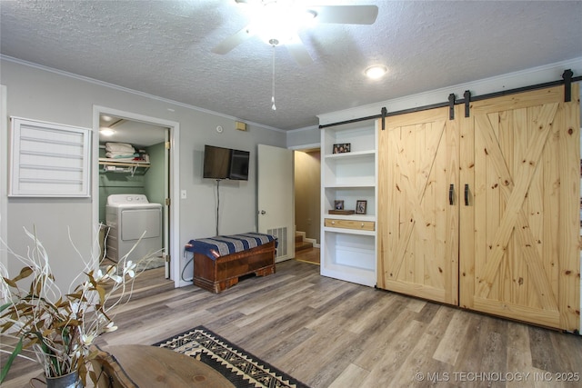 bedroom featuring crown molding, ceiling fan, a textured ceiling, washer / clothes dryer, and a barn door