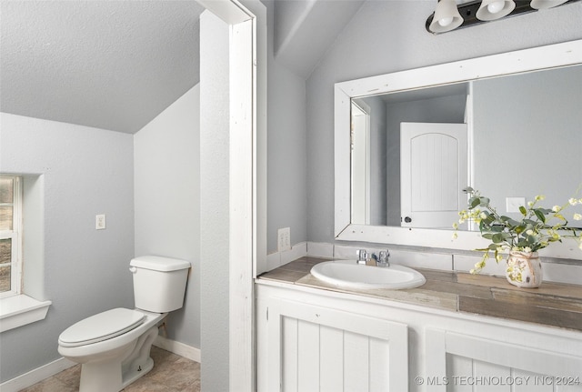 bathroom featuring lofted ceiling, vanity, and toilet