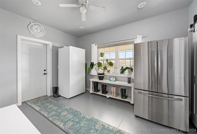 interior space featuring stainless steel fridge, concrete flooring, ceiling fan, and white refrigerator