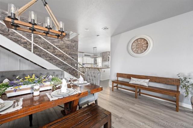 dining area featuring a textured ceiling and light wood-type flooring