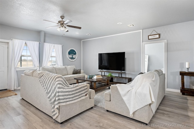 living room featuring ceiling fan, a textured ceiling, and light wood-type flooring