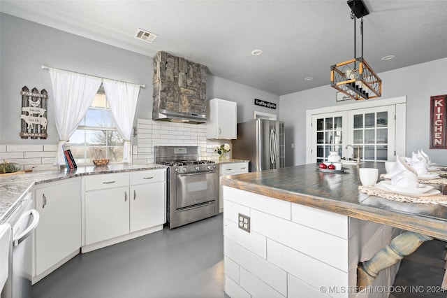 kitchen featuring pendant lighting, white cabinetry, decorative backsplash, stainless steel appliances, and french doors