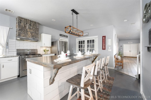 kitchen featuring hanging light fixtures, backsplash, stainless steel appliances, a center island, and white cabinets