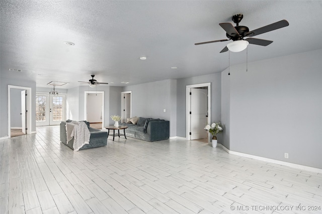 living room featuring french doors, ceiling fan, light hardwood / wood-style floors, and a textured ceiling