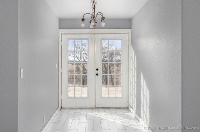 doorway featuring french doors, a healthy amount of sunlight, and a notable chandelier