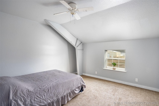 bedroom with ceiling fan, lofted ceiling, carpet floors, and a textured ceiling