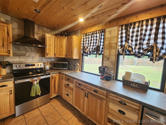 kitchen featuring stainless steel appliances, wood ceiling, wall chimney range hood, backsplash, and dark countertops