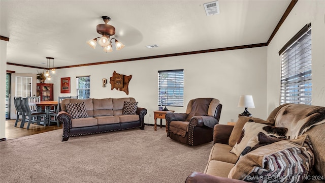 carpeted living room with ceiling fan with notable chandelier and ornamental molding