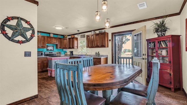 dining space featuring dark hardwood / wood-style floors, crown molding, and sink