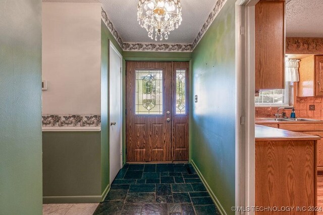 tiled foyer featuring sink, a textured ceiling, and an inviting chandelier