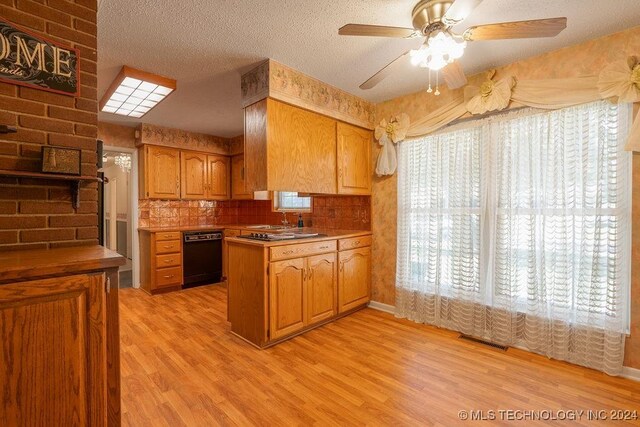 kitchen featuring a wealth of natural light, black dishwasher, and light hardwood / wood-style floors