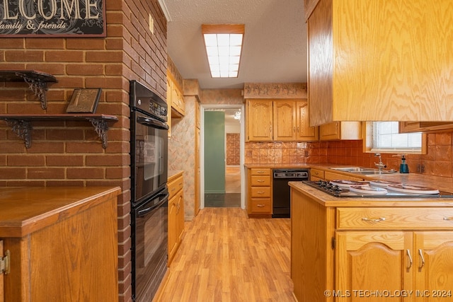 kitchen featuring black appliances, sink, a textured ceiling, and light hardwood / wood-style flooring