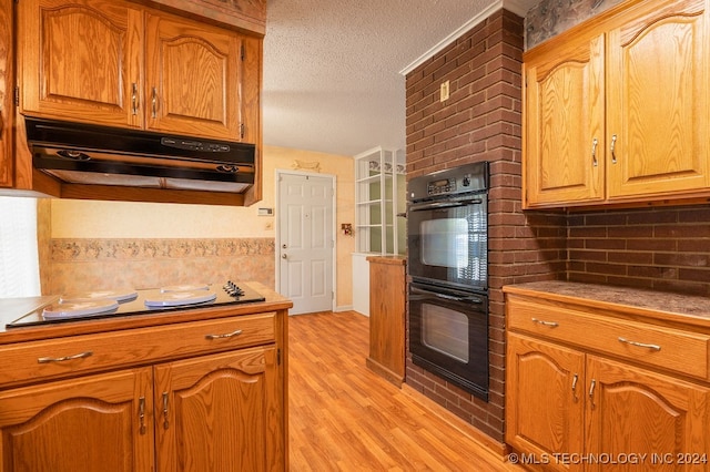 kitchen with light hardwood / wood-style flooring, a textured ceiling, and black double oven