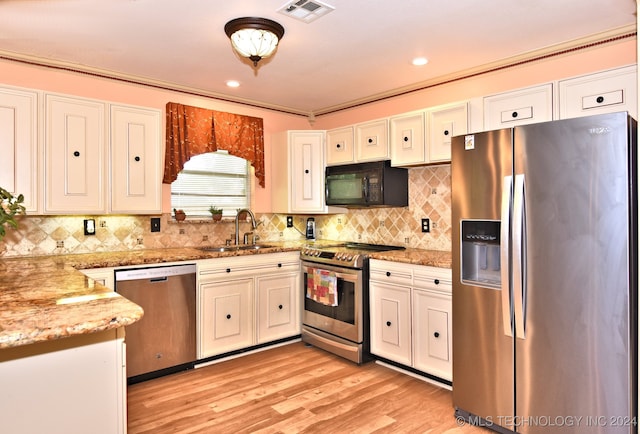 kitchen featuring appliances with stainless steel finishes, light hardwood / wood-style floors, sink, white cabinetry, and light stone counters