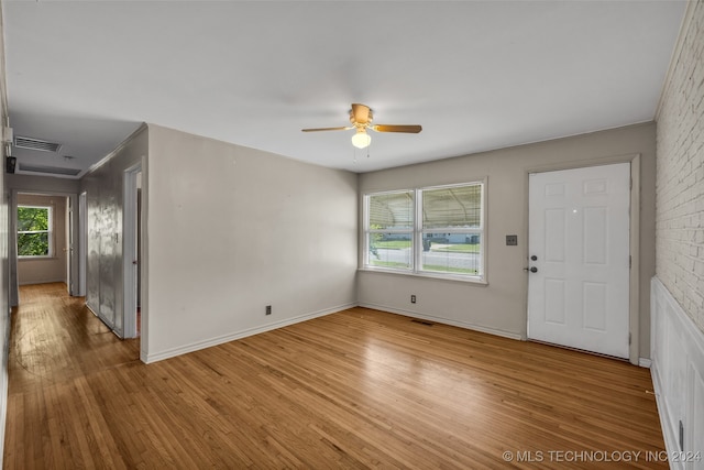 spare room featuring ceiling fan, plenty of natural light, light hardwood / wood-style floors, and brick wall