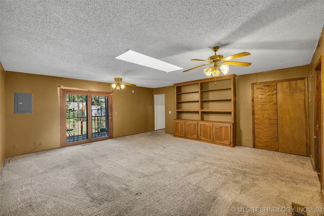 spare room featuring ceiling fan, light colored carpet, a skylight, electric panel, and a textured ceiling