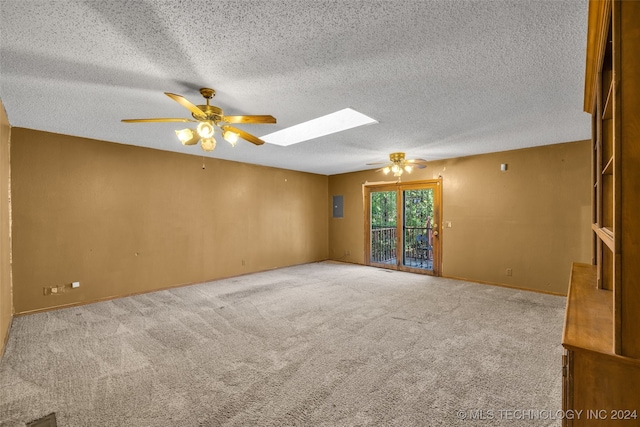 carpeted empty room featuring a textured ceiling, ceiling fan, electric panel, and a skylight