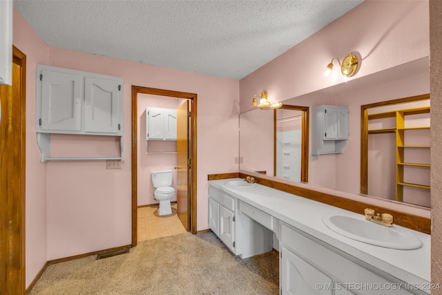 bathroom with double sink vanity, toilet, a textured ceiling, and tile patterned floors