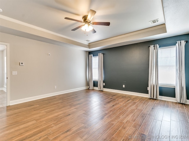 spare room with ceiling fan, light hardwood / wood-style flooring, a tray ceiling, and ornamental molding