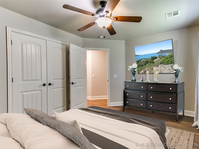 bedroom with ceiling fan, a closet, and dark wood-type flooring