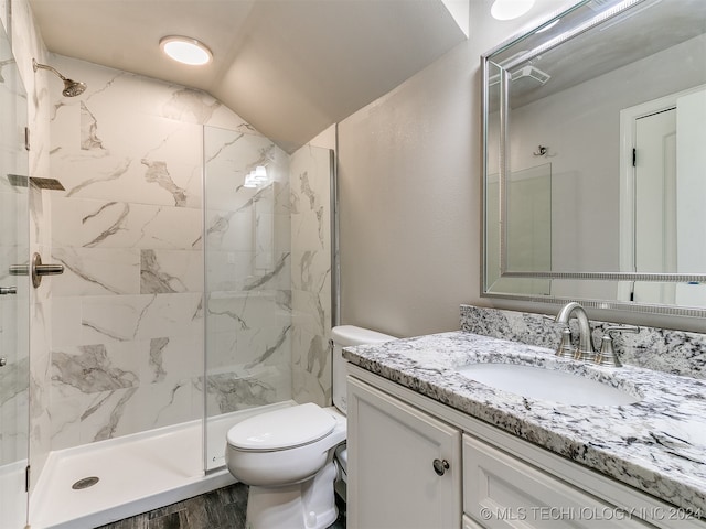 bathroom featuring hardwood / wood-style floors, vanity, lofted ceiling, tiled shower, and toilet