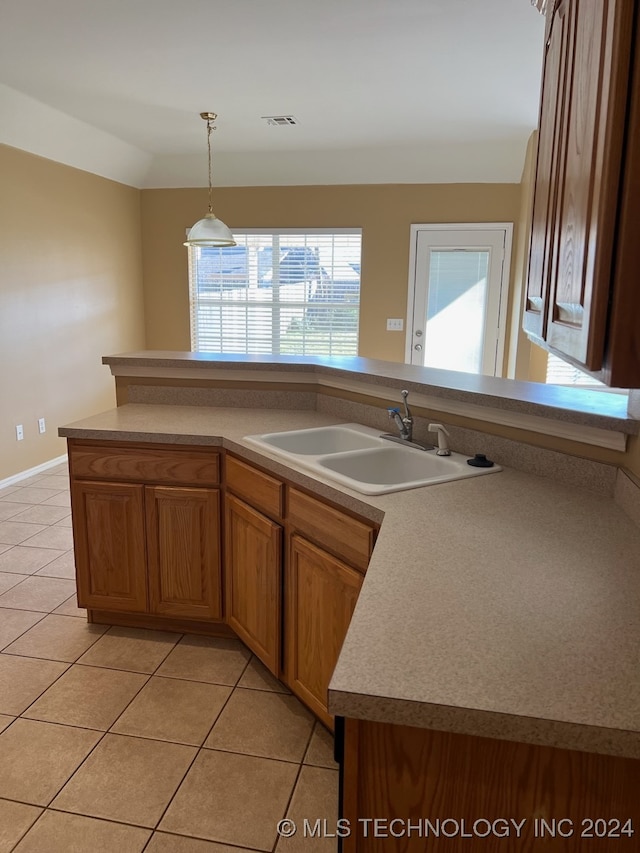 kitchen with light tile patterned floors, sink, and decorative light fixtures