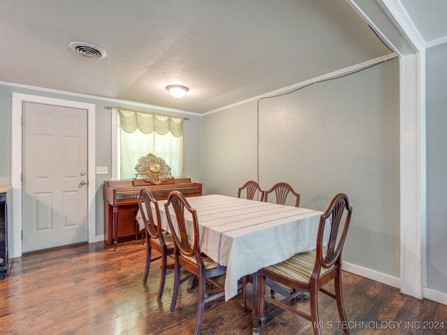 dining room with crown molding and dark wood-type flooring