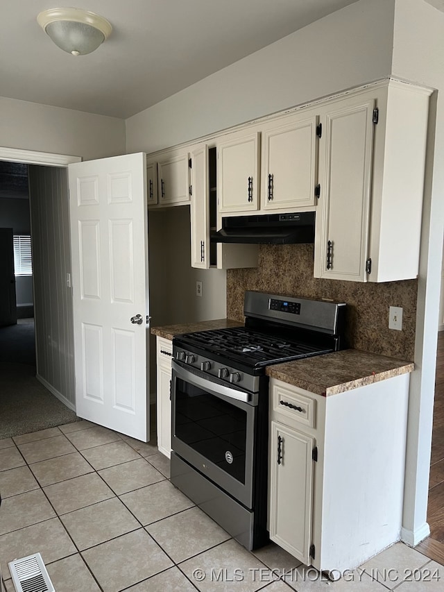 kitchen with white cabinets, tasteful backsplash, stainless steel gas range oven, and range hood