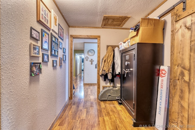 hall with a barn door, hardwood / wood-style flooring, and a textured ceiling