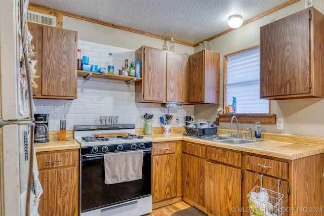 kitchen with backsplash, light hardwood / wood-style flooring, sink, a textured ceiling, and white appliances