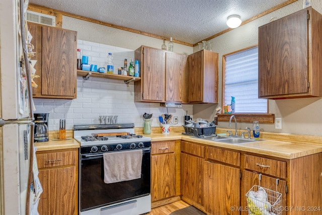 8248 E 122nd Rd, Wetumka, OK 74883 - kitchen with gas range, a sink, light countertops, a textured ceiling, and light wood finished floors