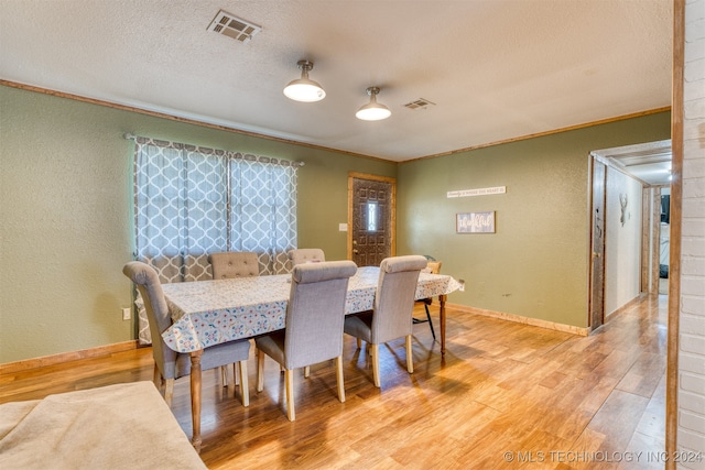 dining space featuring a textured ceiling, crown molding, and wood-type flooring