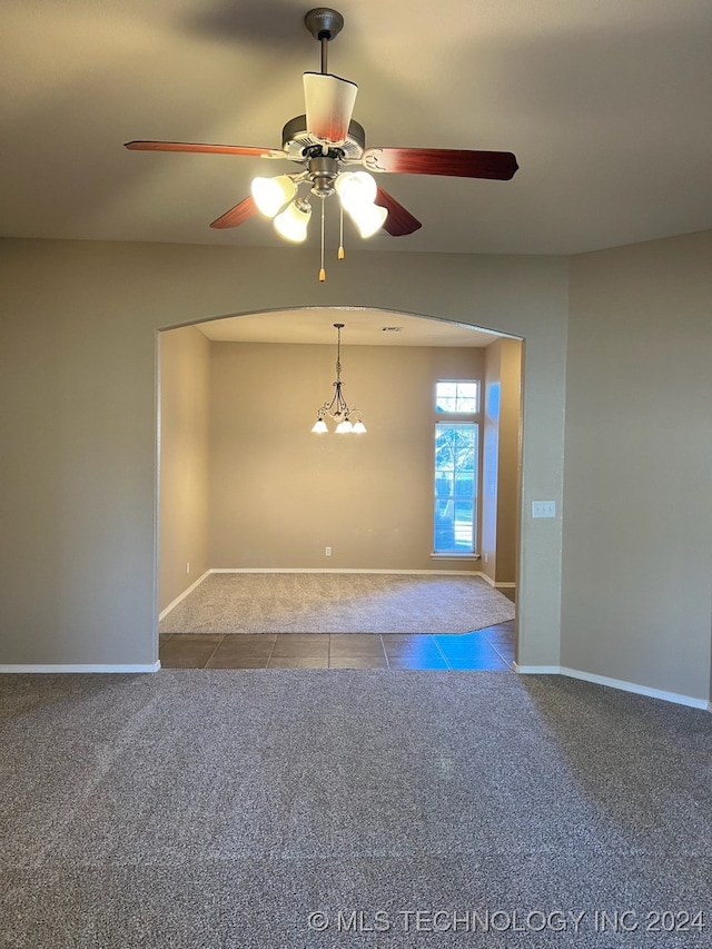 carpeted empty room featuring ceiling fan with notable chandelier