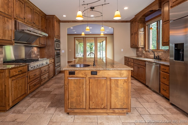 kitchen with hanging light fixtures, a kitchen island with sink, appliances with stainless steel finishes, and plenty of natural light