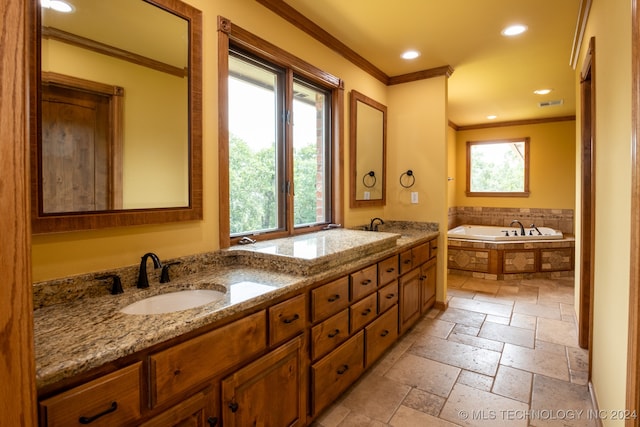 bathroom with ornamental molding, a wealth of natural light, tiled bath, and vanity