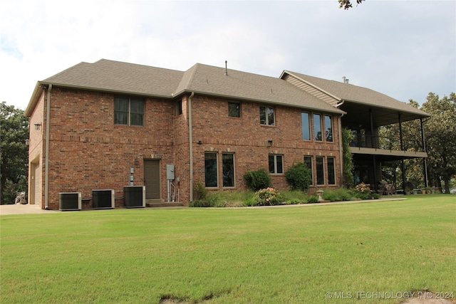 rear view of property featuring a yard and central AC unit