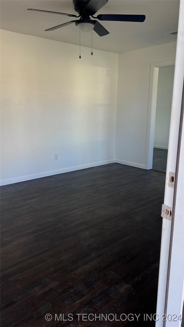 empty room featuring dark wood-style floors, ceiling fan, and baseboards