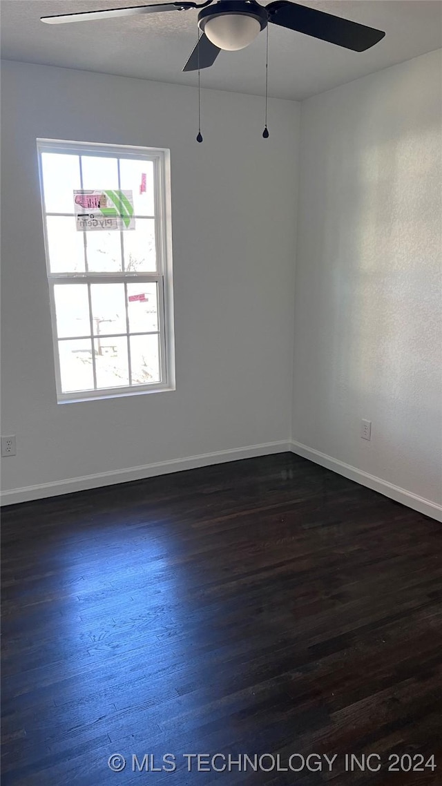 empty room with baseboards, a ceiling fan, and dark wood-style flooring