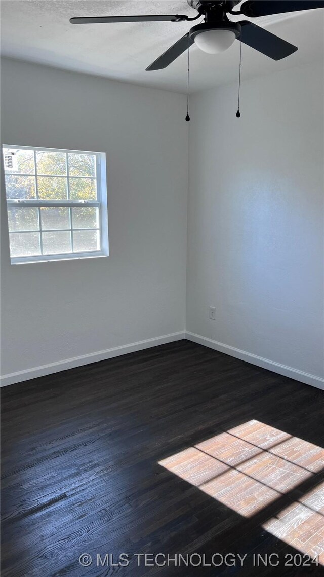 empty room featuring ceiling fan, wood finished floors, and baseboards