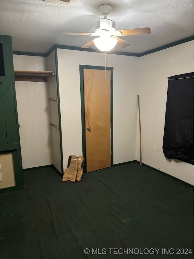 unfurnished bedroom featuring dark colored carpet, ceiling fan, and a textured ceiling