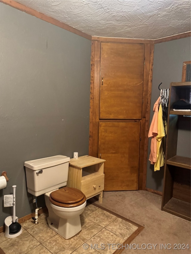 bathroom featuring tile patterned flooring, a textured ceiling, and toilet