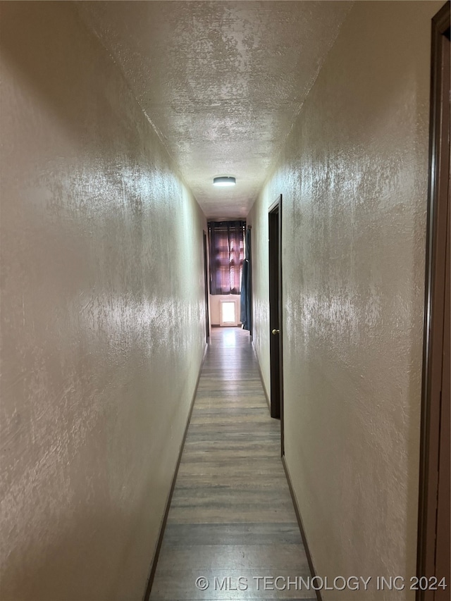 hall with wood-type flooring and a textured ceiling