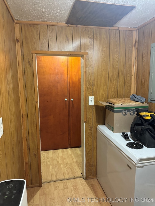 laundry area with light hardwood / wood-style flooring, wooden walls, and a textured ceiling