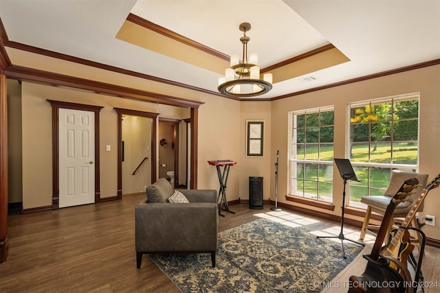 living room with dark hardwood / wood-style floors, ornamental molding, a tray ceiling, and a chandelier