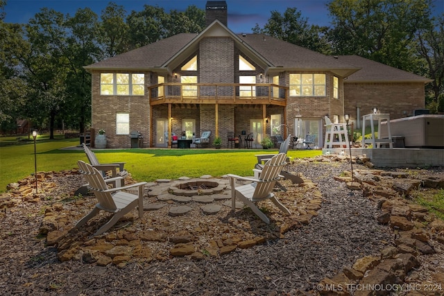 back house at dusk featuring a yard, a patio, and an outdoor fire pit