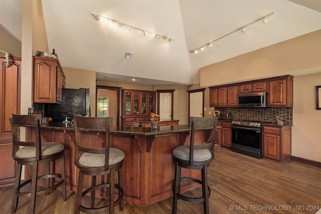 kitchen featuring dark wood-type flooring, a breakfast bar, high vaulted ceiling, stainless steel appliances, and backsplash