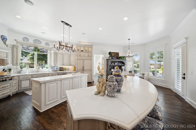 kitchen with ornamental molding, decorative light fixtures, dark wood-type flooring, a chandelier, and a kitchen island