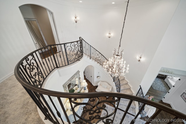 stairs with a towering ceiling, an inviting chandelier, and ornamental molding